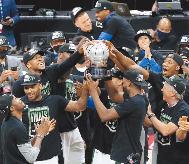 公鹿球员争相碰触东区冠军奖杯庆祝。（美联社）