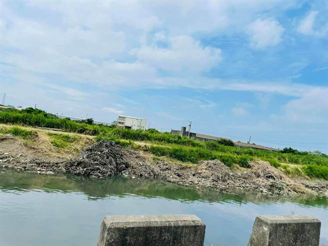 伸港六股水圳岸邊又見堆爛泥雜草，就怕颱風下雨又衝落水，縣府表示只是暫置，包商承諾一定會運走。（賴清美提供／吳敏菁彰化傳真）