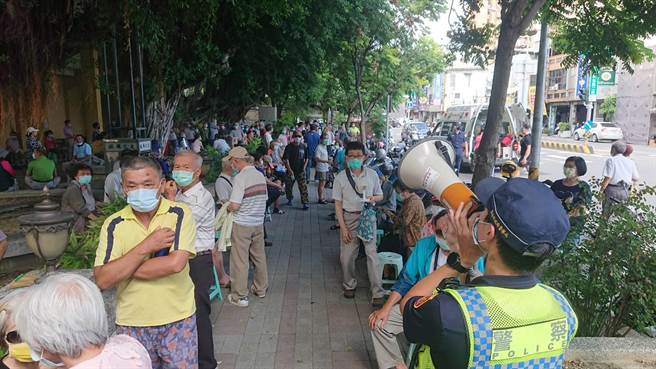 中西区协进国小疫苗接种站10日引爆群聚人潮，警方以大声公扩音器维持秩序，有长辈受不了在艷阳下等候出现中暑症状，请来救护车送医。（程炳璋摄）