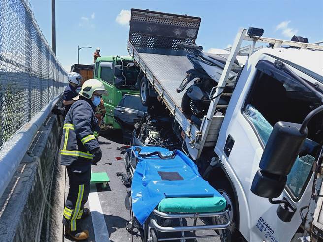 台64線八里匝道口14日上午10時許發生連環車禍，2輛小貨車遭到2輛砂石車包夾，其中白色小貨車駕駛被救出後仍舊傷重不治。（新北消防提供）