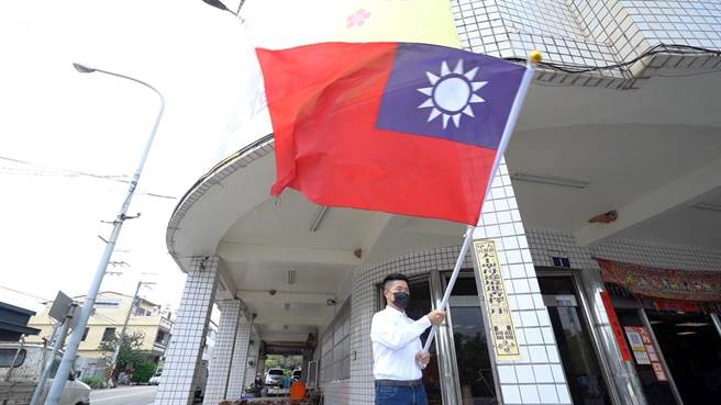 「我们爱这个国家，希望国家也能够一样爱我们。」前立委顏宽恒在服务处前挥舞国旗。（顏宽恒服务处提供／王文吉台中传真）