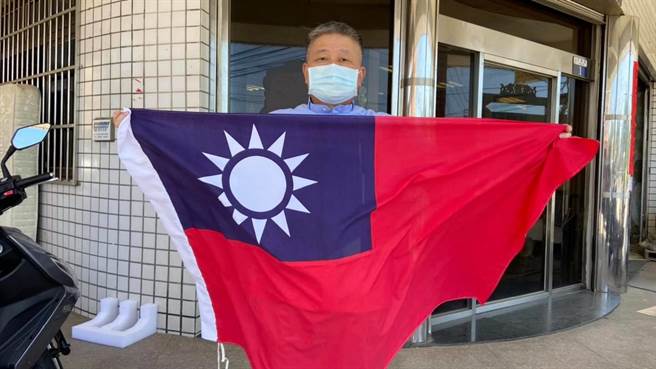 镇澜宫董事长顏清标在儿女服务处前响应与国旗合照。（顏宽恒服务处提供／王文吉台中传真）