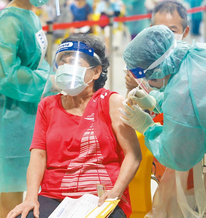 台北市大型疫苗接种站（花博争艳馆）14日启用，医护人员帮民眾施打疫苗时，民眾面露痛苦表情。（刘宗龙摄）