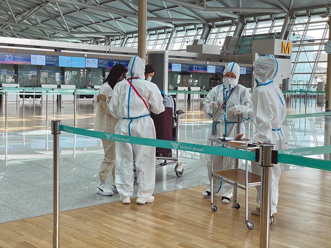 南韓第4波疫情持續蔓延，當局14日發布單日新增確診衝上1615例的歷來新高。圖為韓國仁川國際機場工作人員嚴格執行防疫措施。（中新社）