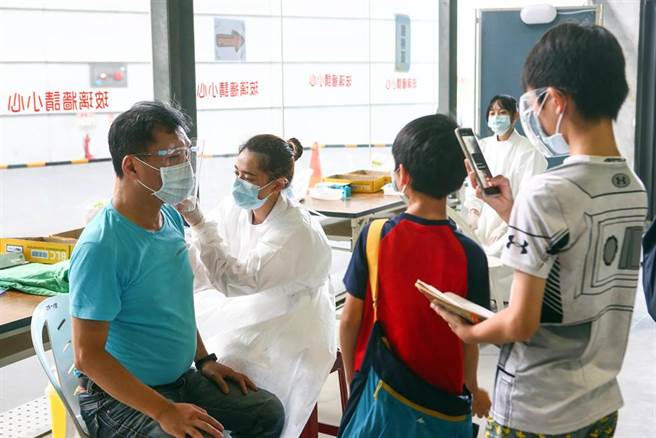 台北市政府与三军总医院在台北市网球中心合办施打疫苗，16日改打AZ疫苗，陆续有民眾前往接种，有民眾带着小孩一起前往接种站，小孩拿起手机帮爸爸纪录施打疫苗的一刻。（邓博仁摄）