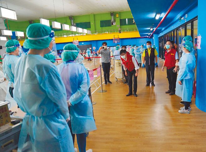 高雄巿长陈其迈（中）15日视察接种站，并向医护人员鞠躬。（高巿府提供／曹明正高雄传真）