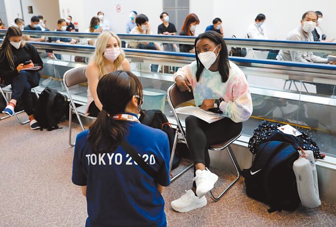 美国体操天后拜尔丝（右）抵达东京成田机场后，东奥工作人员协助报到。（路透）