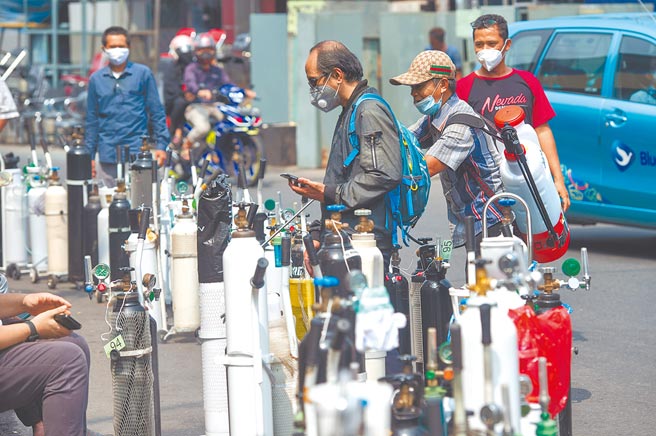 高傳染性的Delta變種病毒株在印尼肆虐，導致單日確診連續破五萬大關，印尼已取代印度，成為當前亞洲疫情震央。在首都雅加達，民眾戴著口罩排隊為氧氣罐充氧。（新華社）