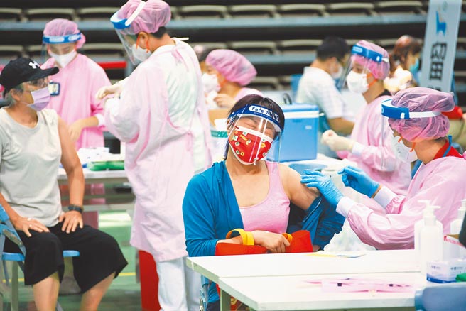 新庄综合体育馆17日疫苗接种相当踊跃，有医护人员帮忙接种疫苗时，民眾露出疼痛表情。(罗永铭摄）