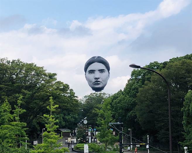 东京都上空近日出现一颗巨大的人头气球，一现身就吸引不少日本民眾驻足拍照。（图片翻摄自推特/@uzzy55）