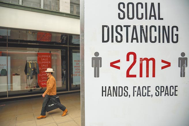 英国单日新增新冠确诊病例连续两天突破5万人，完整注射2剂AZ疫苗的卫生大臣贾维德17日也证实受感染，出现轻微症状。图为在英国伦敦，一名男子从提示人们保持社交距离的牌子旁走过。（新华社）