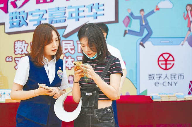 中国人民银行（大陆央行）近日发布《中国数字人民币的研发进展白皮书》，即便外国人也可透过数位人民币钱包享受基础金融服务。图为交通银行北京市分行的工作人员（左）引导游客李女士开通数位人民币钱包。（新华社）