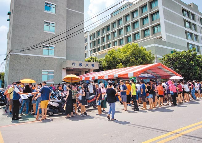 云林基督教医院18日开放18岁以上民眾现场拿号码牌接种疫苗300个名额，清晨5点半就有人排队，云林县议员李明哲（左一）发送防护罩给现场等候打疫苗的民眾。（周丽兰摄）