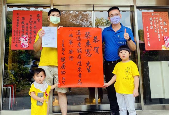 蜂农蔡杰宪（左）通过蜂蜜产销履歷验证，台东县政府农业处人员代表县长前往贴红榜祝贺。（台东县政府提供）