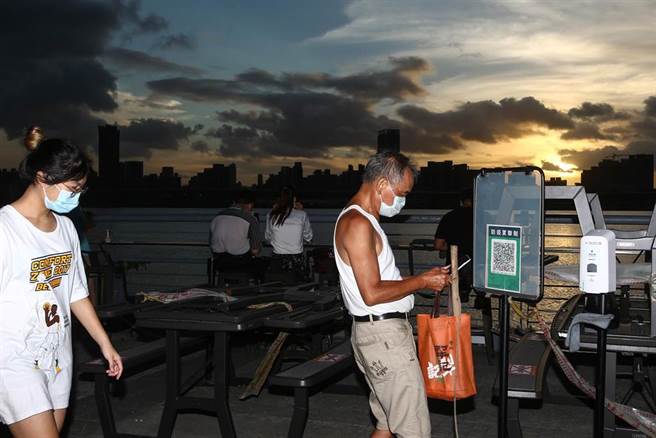 輕颱烟花行進慢、路徑直逼台灣東北角，微解封後20日傍晚許多民眾前往大稻埕賞夕陽，民眾進入時還得實名制才得進入，形成一幅現代風景。（鄧博仁攝）