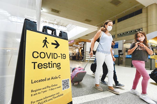 专家警告，解封后英国每天新增新冠确诊病例可能会破20万，并对卫生医疗系统造成重大破坏。届时强森政府可能又要难堪地髮夹弯，重新实施防疫措施。图为佩戴口罩的旅客走过一块新冠检测告示牌。（新华社）