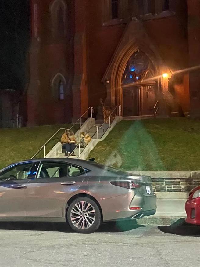 送餐的一个晚上，看到一位流浪老人坐在教堂台阶上吃饭，一只大黄狗陪着他，灯光很暖。（作者提供）