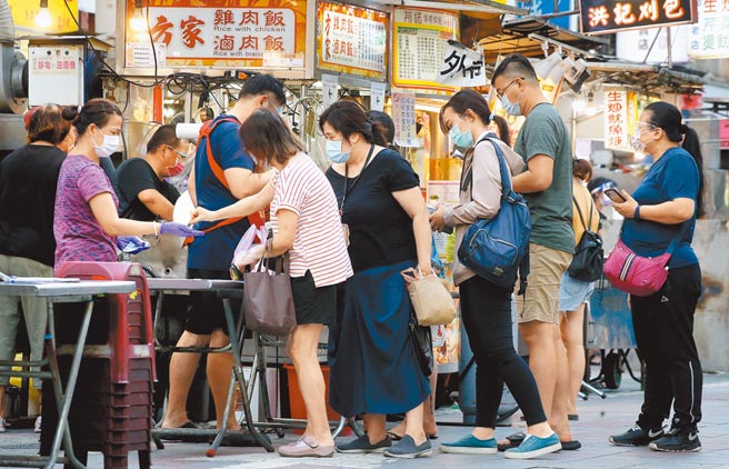 新冠肺炎疫情重创餐饮业，行政院已商请国发会及各相关部会盘点规画振兴方案，并研议发放振兴券抢救餐饮业，在寧夏夜市中，购物的民眾排队取餐。（范扬光摄）