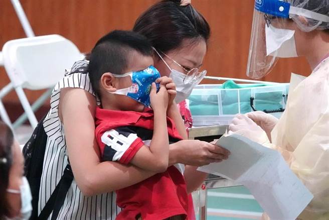 1位陪同家长前来的小男童，用口罩遮住眼睛，不敢直视打针画面。（黄世麒摄）
