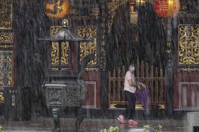 信徒22日冒著中颱「烟花」帶來的大雨前往台北市保安宮上香，保安宮是目前微解封首座開放上香的寺廟；中央流行疫情指揮中心指揮官陳時中表示，三級警戒26日可望降級，相關解封單位正在研議中。(黃子明攝)