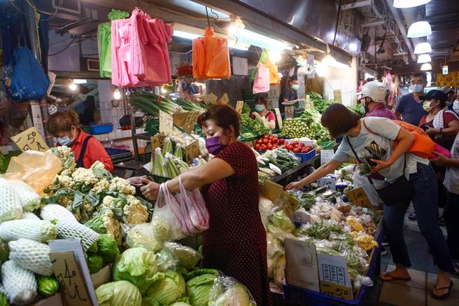 烟花颱風來勢洶洶，但因從台灣擦邊過，一連兩天飆漲的產地蔬菜，23日交易疲軟迅速回跌。民眾也趁著雨勢稍緩，一早即到市場買菜。（鄧博仁攝）