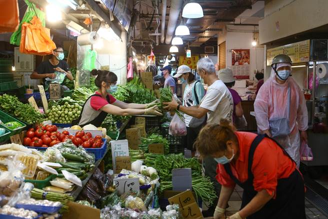 烟花颱風來勢洶洶，但因從台灣擦邊過，一連兩天飆漲的產地蔬菜，23日交易疲軟迅速回跌。民眾也趁著雨勢稍緩，一早即到市場買菜。（鄧博仁攝）