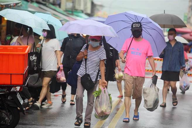 中央流行疫情指挥中心日前宣布7月27日到8月9日调降疫情警戒标准至第二级，市场取消身分证分流，摊商仍维持双罩一套，民眾24日在滨江市场冒雨购买蔬果。（张铠乙摄）
