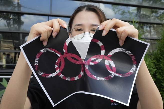 1名学生撕毁有旭日旗样貌的奥运标志文宣品。(图/美联社)