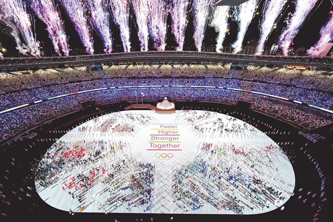 2020东京奥运开幕式，各国运动员在电玩交响乐中进入新国立竞技场后，场中央打出更快、更高、更强的奥运格言，及面对新冠疫情要「更团结」的口号。（美联社）