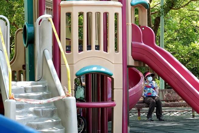 民眾戴着口罩到运动公园乘凉，疫情前假日总是挤满孩童的游乐设施依旧封闭。（图／记者黄世麒摄影）
