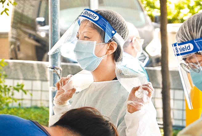 户外採检站穿着防护衣又无法吹冷气的护理人员，于炎夏中以自制简易冰水袋敷在脖子上降温，抵御酷暑。（本报资料照片）