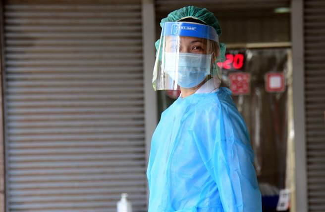 台东连续两天飙高温并且刮焚风，部东医院护理师在骑楼下穿着隔离衣值班，站3分钟就大暴汗。（庄哲权摄）