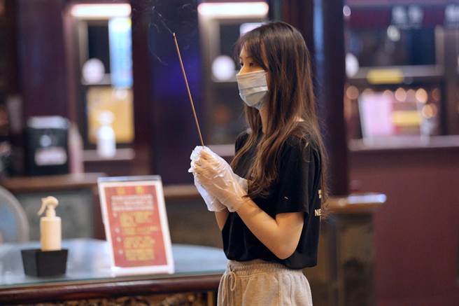 民眾戴上拋棄式手套捻香參拜。（黃世麒攝）