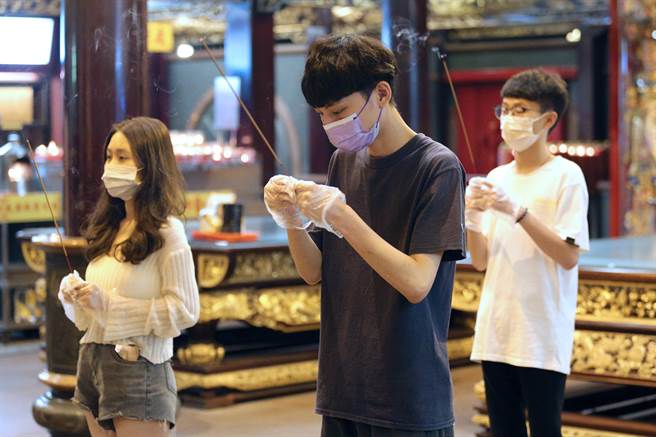 民眾戴上拋棄式手套捻香參拜。（黃世麒攝）