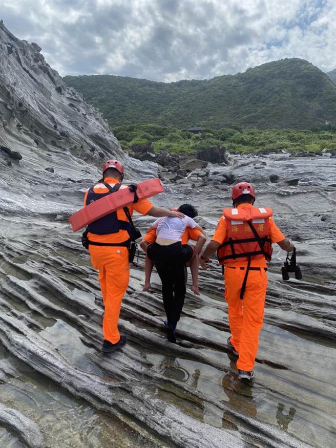 海巡人员在花莲县丰滨乡的石梯坪礁岩区发现陈女后将她背上岸，由救护人员送医救治。（海巡署东部分署第一二岸巡队提供／罗亦晽花莲传真）