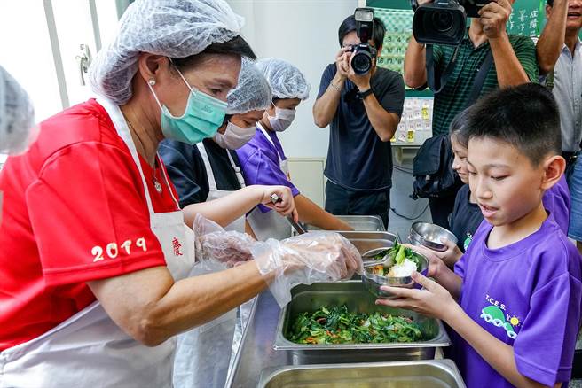 宜兰县政府向中央争取经费，推动「偏乡学校中央厨房计画」，图为县长林姿妙（左）在实施免费营养午餐政策首日，为学童打菜。（本报资料照片）