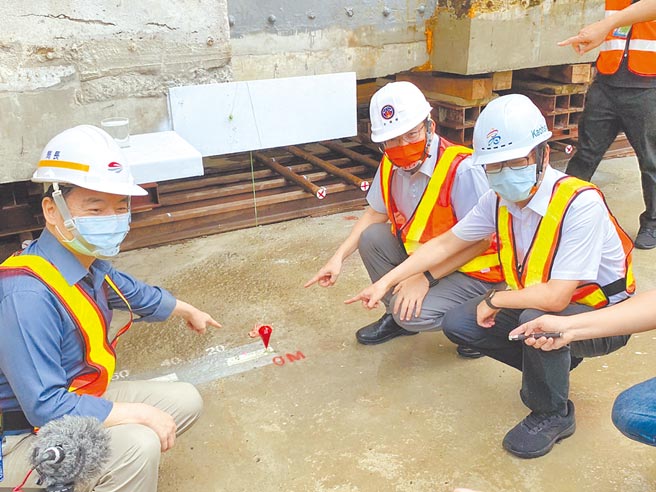 交通部长王国材（中）、立委李昆泽（右一）及交通部官员一行人26日见证高雄帝冠车站启动迁移回娘家。图中红色箭头处为车站建筑体开始启动的位置，将先向北挪移4.8公尺，再向西挪移57.86公尺后，完成永久定位。（石秀华摄）