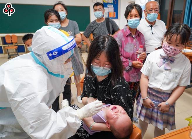 南京新增新冠本土病例仍集中机场周边，发现多起群聚性疫情。图为7月24日，医护人员在南京市江寧区龙西社区核酸检测点为小朋友进行核酸检测取样。（新华社）