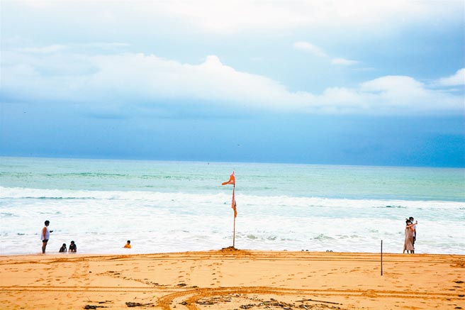 警戒降级首日垦丁南湾因浪大插红旗，但一早仍出现零星游客，以亲子客居多，戏水玩得不亦乐乎。（谢佳潾摄）