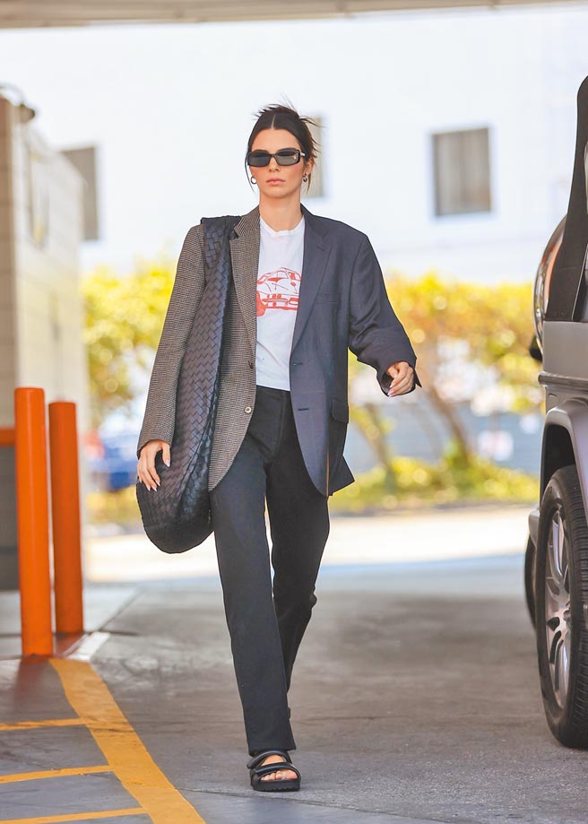坎达儿珍娜以白色印花T恤搭配黑裤、凉鞋，外搭格纹西装外套、Bottega Veneta Maxi Jodie包，现身比佛利山庄。（CFP）