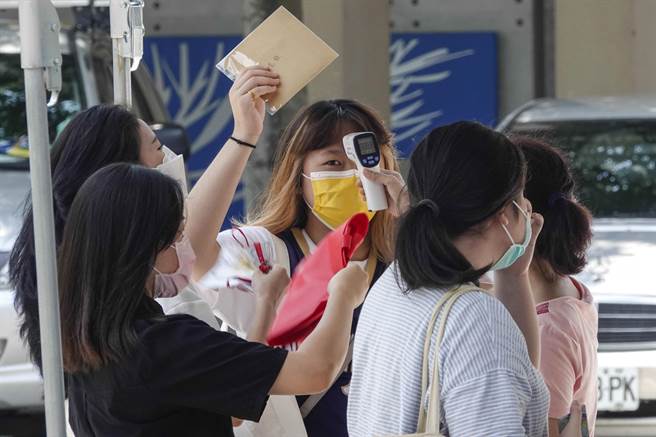 北市立松山家商毕业生返校活动，因天气炎热，许多人体温超标被挡在校门口，有人搧风降温，才得以获准进入校园。（黄子明摄）