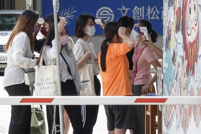 北市立松山家商毕业生返校活动，因天气炎热，许多人体温超标被挡在校门口，有人搧风，有人用冰水瓶降温，才得以获准进入校园。（黄子明摄）