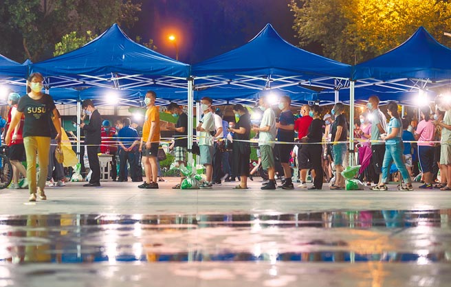 大陆江苏南京疫情仍未控制，当地不断进行核酸检测取样。图为28日晚市民排队等取样。（中新社）