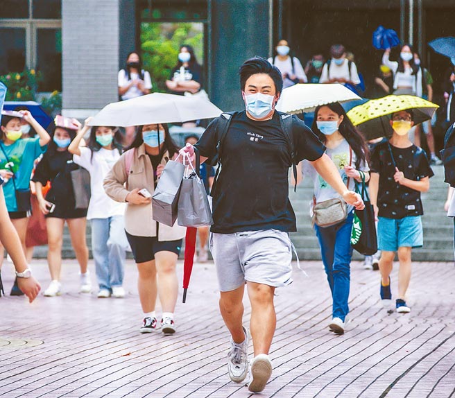 大學指考30日畫下圓滿句點，考生興奮在大雨中奔跑離開考場。(羅永銘攝）