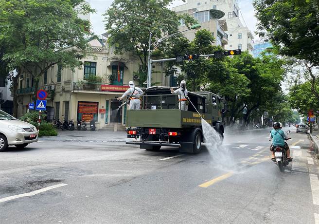 越南政府表示，從8月2日起，商業中心胡志明市與其他18個南部省、市將延長2週封城令。圖為越南衛生人員消毒街道。（圖／路透社）
