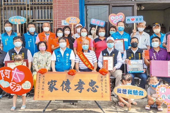 田馥甄百岁外公宋增土（前排右二）获选新竹县模范父亲，她（红圈处）高举牌子庆贺。（罗浚滨摄）