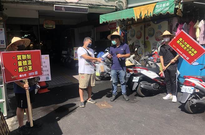 南屯热血青年合体组成「市场防疫宣导员」，在南屯市场入口帮忙买菜族喷酒精、举牌提醒，甚至拿起麦克风宣导。（「南屯即时通」粉专提供）