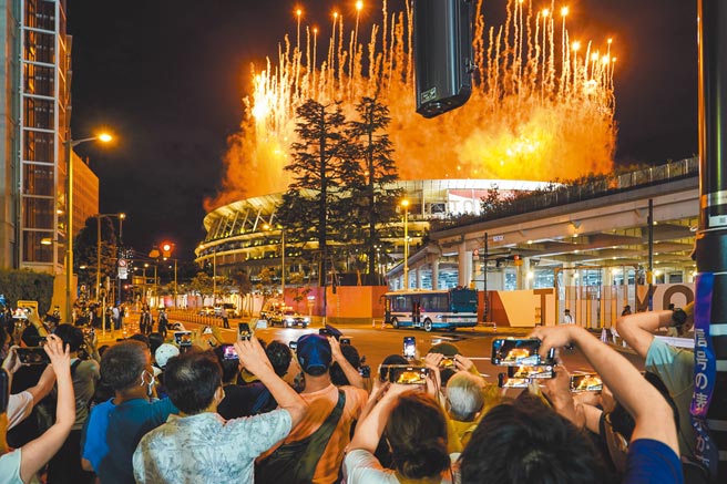 由于防疫疲劳加上奥运让民眾松懈，导致日本疫情不断蔓延。图为7月23日东京奥运开幕式当晚，民眾聚集在新国立竞技场外观看烟火。（新华社）
