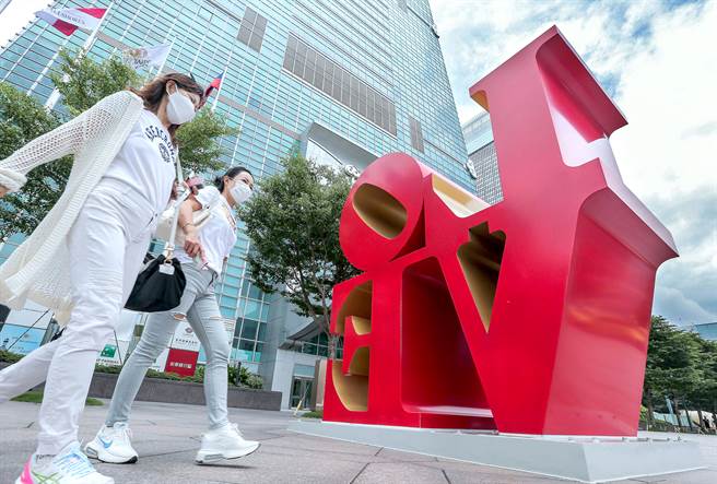 台北101商场5楼精品专柜日前一名员工确诊，随即在傍晚18时暂停营业并进行全馆消毒，4日商场部分休馆一天。中午用餐时间，附近上班族及其他民眾纷纷外出用餐，两位民眾行经大楼前着名地标。(粘耿豪摄)