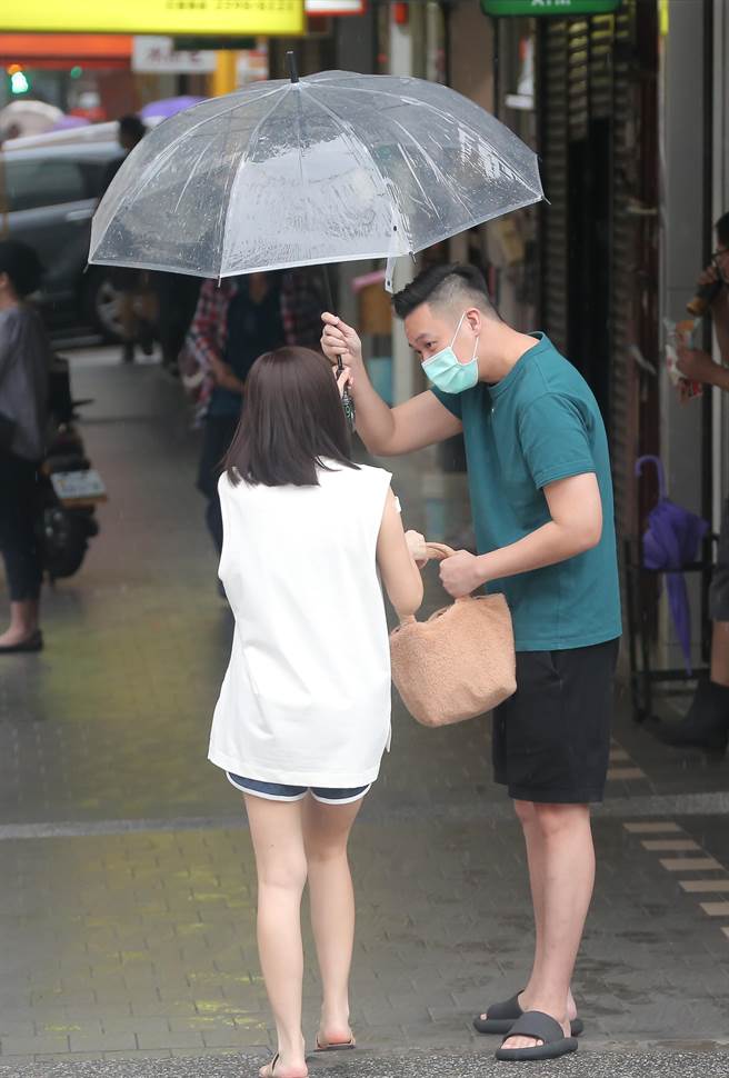 鍾欣怡打完疫苗後，老公孫樂欣趕緊替她撐傘、拿包包，十分貼心。（羅永銘攝）